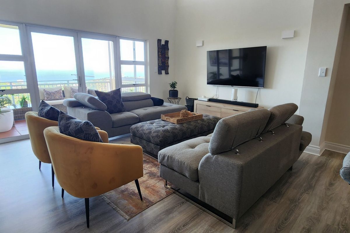 Spacious living room featuring high ceilings, modern laminate flooring, and large glass sliding doors that provide abundant natural light and access to the balcony.