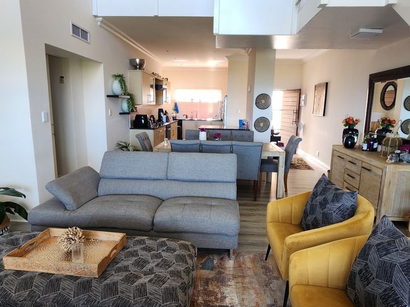 Spacious open-plan living and dining area featuring a modern kitchen, neutral finishes, and a staircase leading to the upper level.