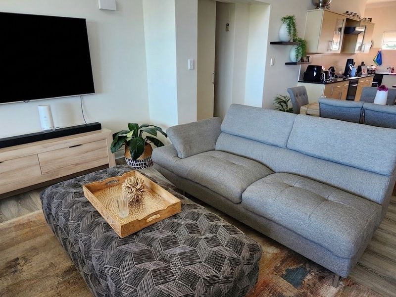 Open plan living and dining area featuring modern laminate flooring and a functional kitchen with built-in cabinetry and integrated appliances.