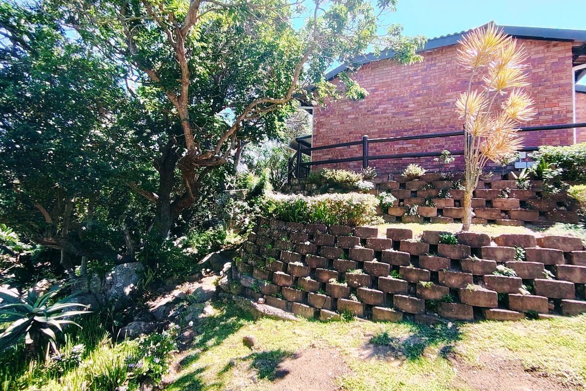 Rear exterior view of the townhouse featuring a tiered brick retaining wall, established garden landscaping, and a brick building facade with timber railing.