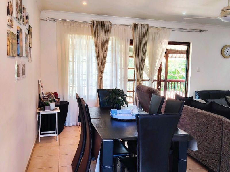 Open-plan living and dining area featuring tiled flooring, ceiling fan, and sliding glass doors providing access to the outdoor space.