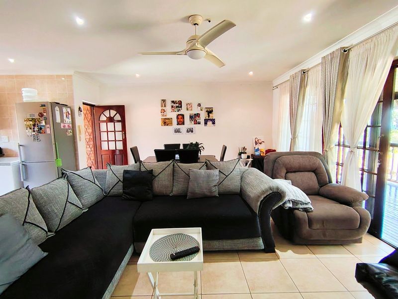 Spacious open-plan living and dining area featuring tiled flooring, recessed lighting, a ceiling fan, and large sliding glass doors leading to the exterior.