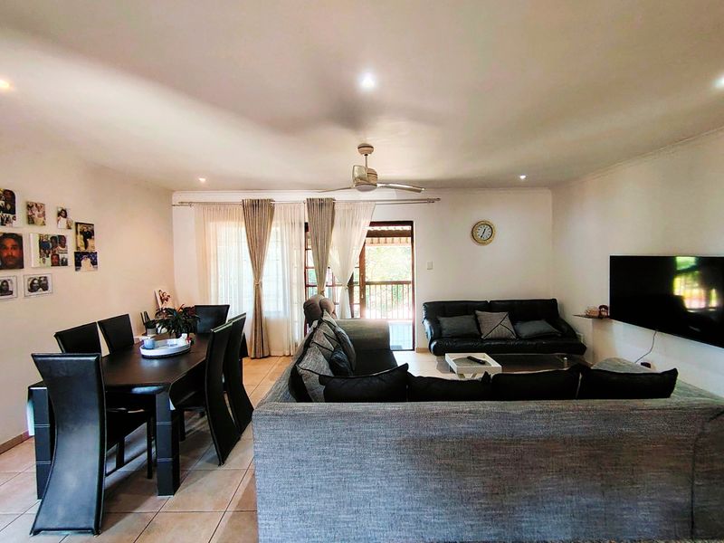 Spacious open-plan living and dining area featuring tiled flooring, recessed lighting, a ceiling fan, and direct access to an outdoor patio through sliding doors.