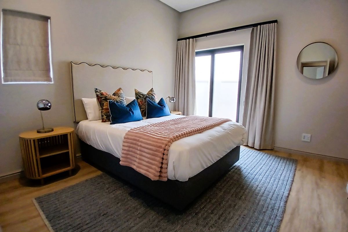 A well-maintained bedroom featuring laminate flooring, recessed lighting, and a sliding glass door providing natural light.