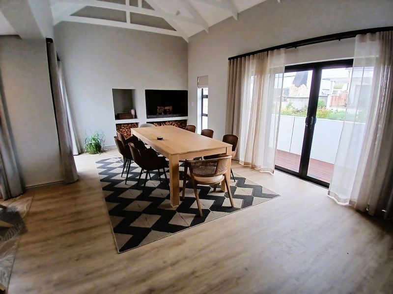 Spacious dining area featuring a vaulted ceiling, built-in fireplace with wood storage, and large sliding glass doors opening to an outdoor balcony.