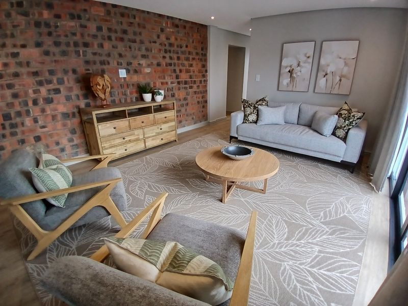 A well-presented living room featuring a striking exposed brick feature wall, modern recessed lighting, and durable laminate flooring.