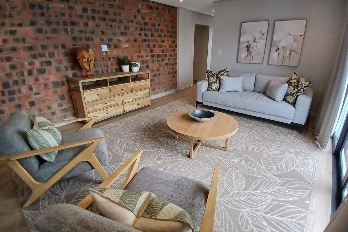 A well-presented living room featuring a striking exposed brick feature wall, modern recessed lighting, and durable laminate flooring.