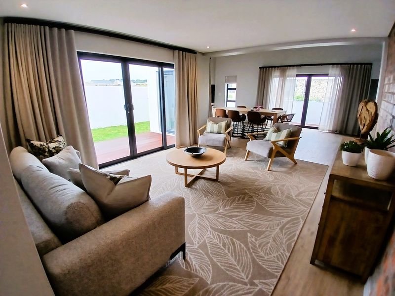 Spacious open-plan living and dining area featuring modern laminate flooring, recessed lighting, and large sliding glass doors opening to an outdoor patio.