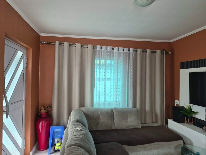 A living room featuring terracotta-toned walls, a security gate, and a window with curtain fixtures.