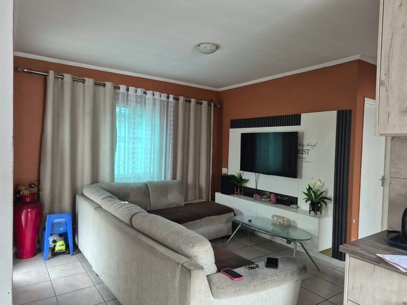 A comfortable living room featuring tiled flooring and a built-in media unit, providing a functional space for relaxation and entertainment.