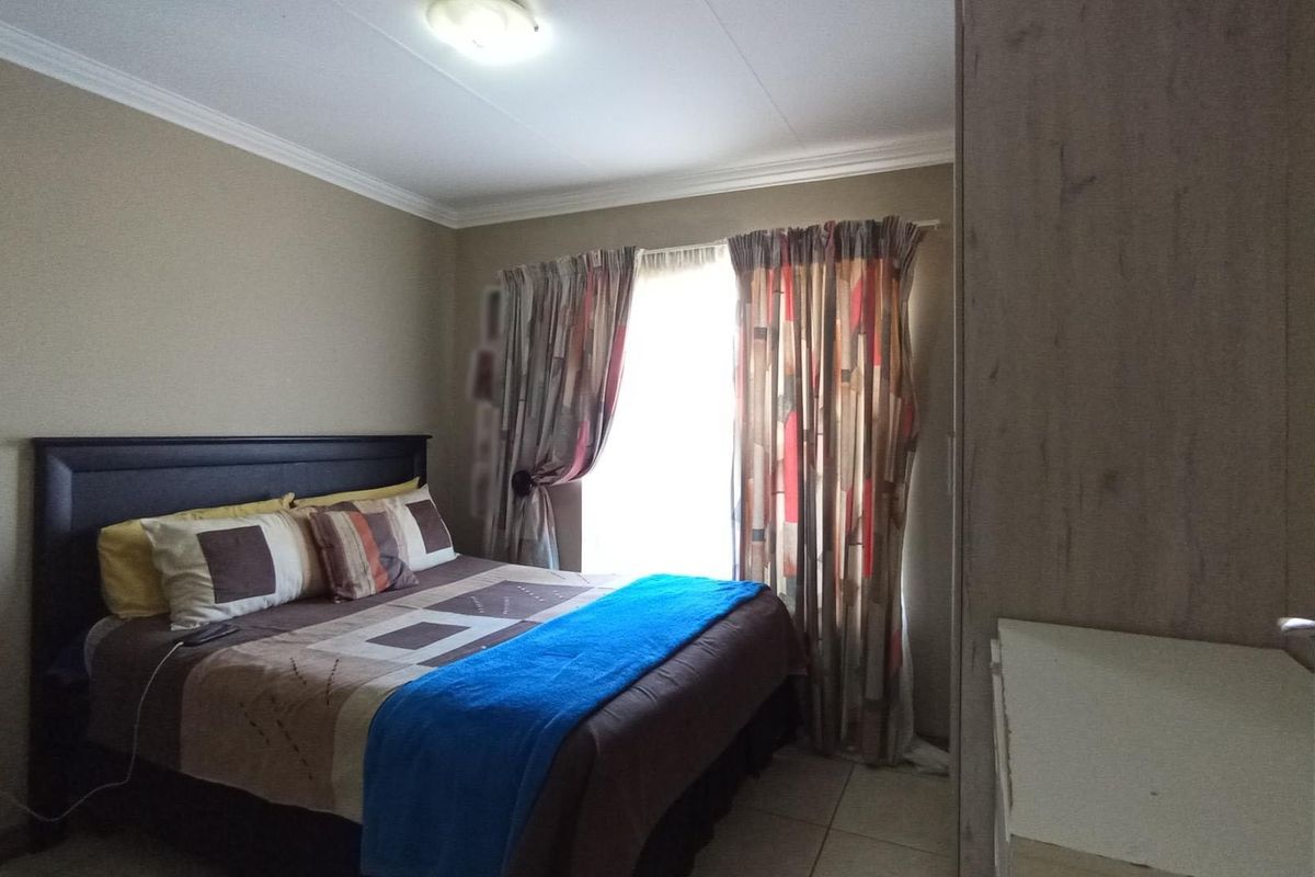 A functional bedroom featuring tiled flooring, ceiling cornices, and a built-in cupboard, offering a neutral base for personalization.