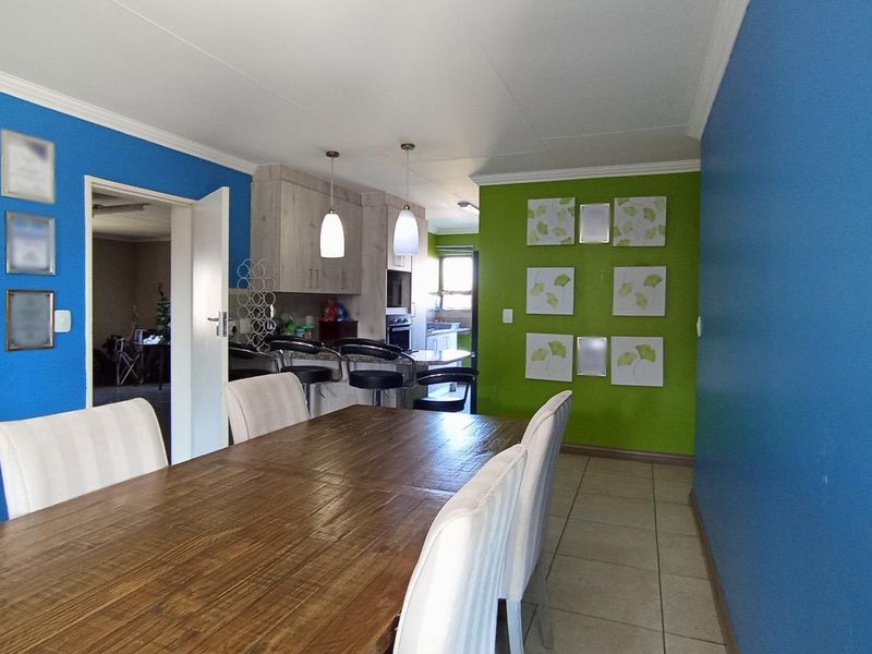 Open plan dining and kitchen area featuring tiled flooring, modern cabinetry, and a central kitchen island with pendant lighting.