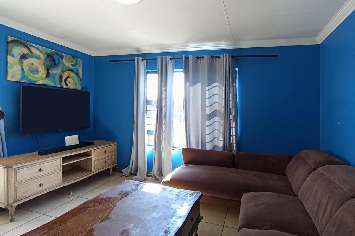 A living room featuring tiled flooring and crown molding, finished with bold blue wall paint.