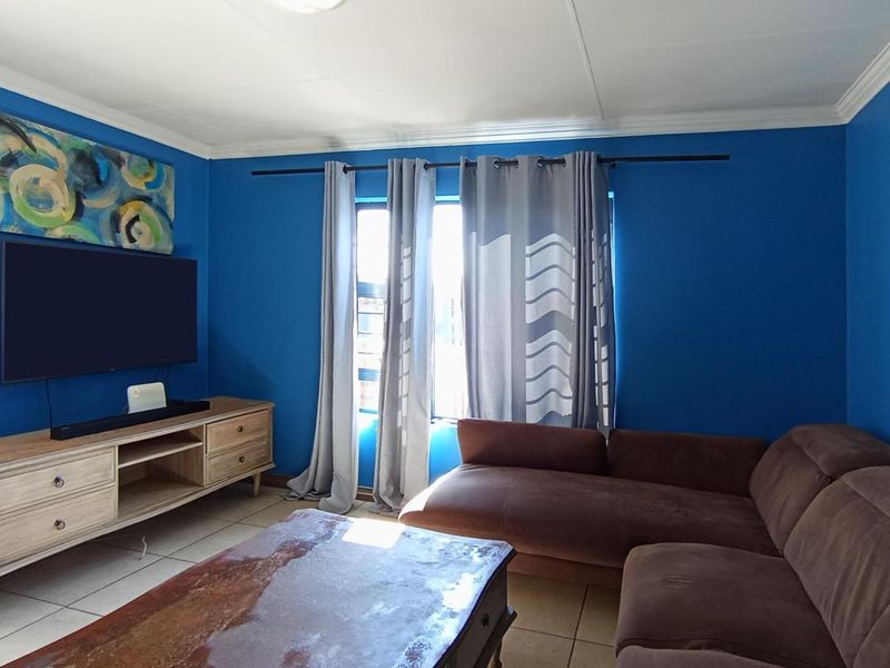 A living room featuring tiled flooring and crown molding, finished with bold blue wall paint.