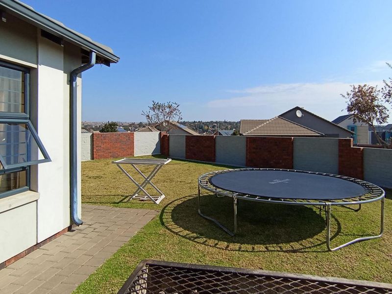 A private rear garden featuring a paved patio area, a well-maintained lawn, and secure brick boundary walls.