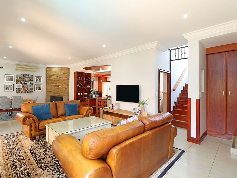 Spacious open-plan living area featuring a stone fireplace, built-in wine storage, and a wooden staircase leading to the upper level.