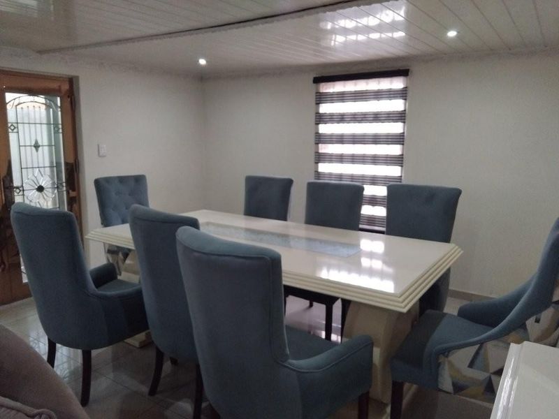 A dining room featuring tiled flooring, recessed downlighting, and a panelled ceiling, providing a functional space for family meals.