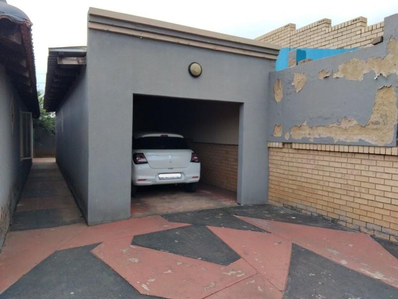 A single garage structure with a paved driveway and adjacent brick boundary wall showing signs of exterior finish deterioration.