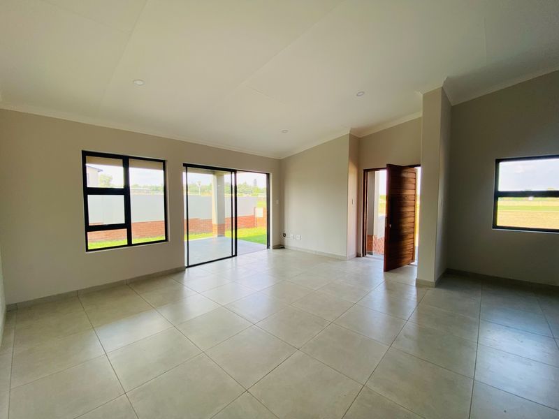 Spacious, light-filled living area featuring neutral tiled flooring, recessed lighting, and direct access to the outdoor patio through sliding glass doors.