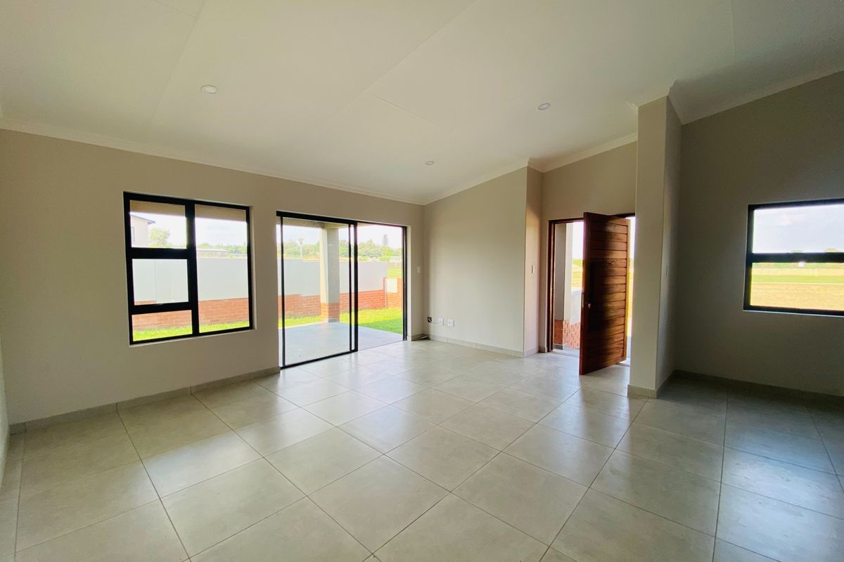 Spacious, light-filled living area featuring neutral tiled flooring, recessed lighting, and direct access to the outdoor patio through sliding glass doors.