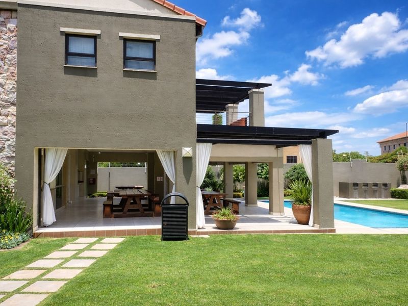 Rear view of the property featuring a covered patio area, swimming pool, and well-maintained garden with stone-clad exterior wall details.
