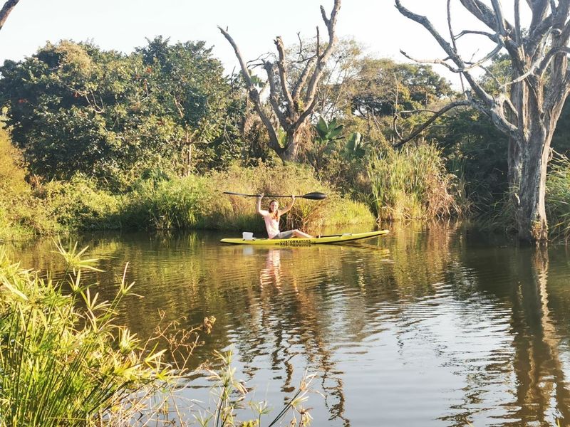 A scenic view of a natural water feature on the property, surrounded by mature trees and lush indigenous vegetation.
