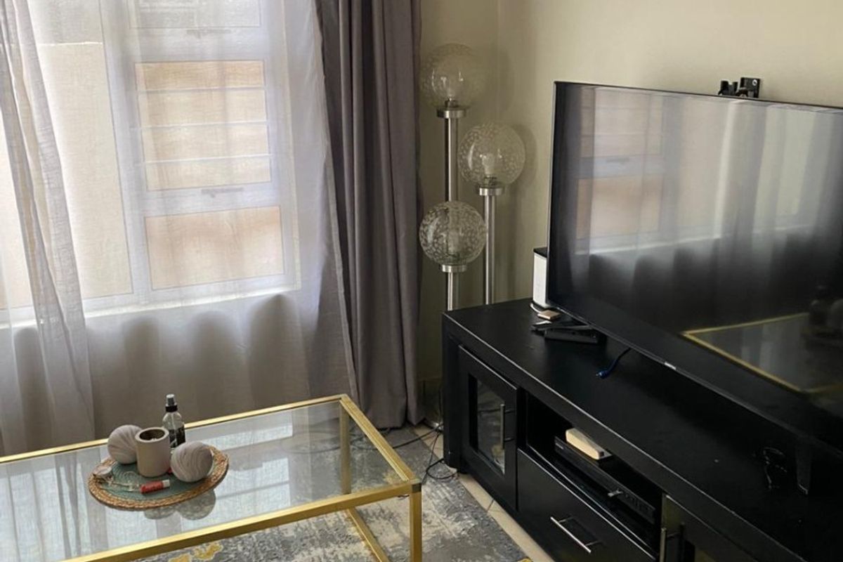 A compact living room area featuring tiled flooring and window treatments, providing a functional space for relaxation.