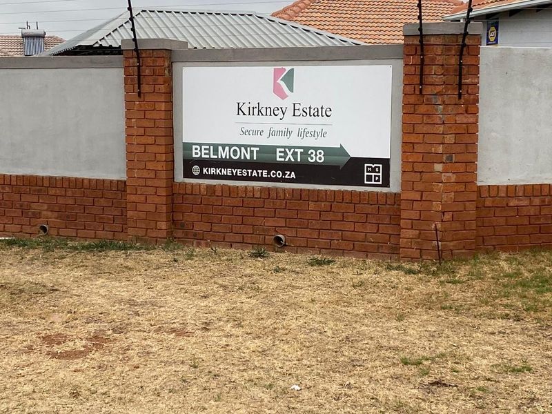 A brick boundary wall featuring estate signage and integrated electric fencing, marking the entrance to the Kirkney Estate residential development.