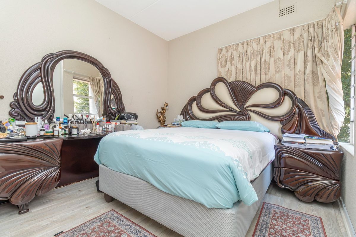 A standard bedroom featuring neutral wall finishes, a ventilation grille, and window treatments.