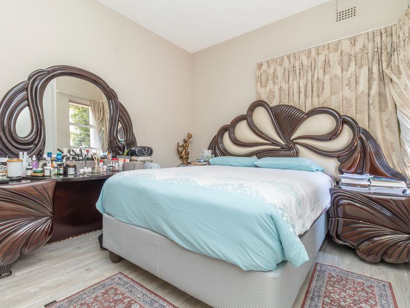 A standard bedroom featuring neutral wall finishes, a ventilation grille, and window treatments.