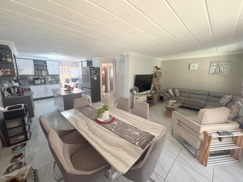 Spacious open-plan living area featuring a modern kitchen with island, dining space, and lounge, finished with contemporary floor tiles and a clean aesthetic.