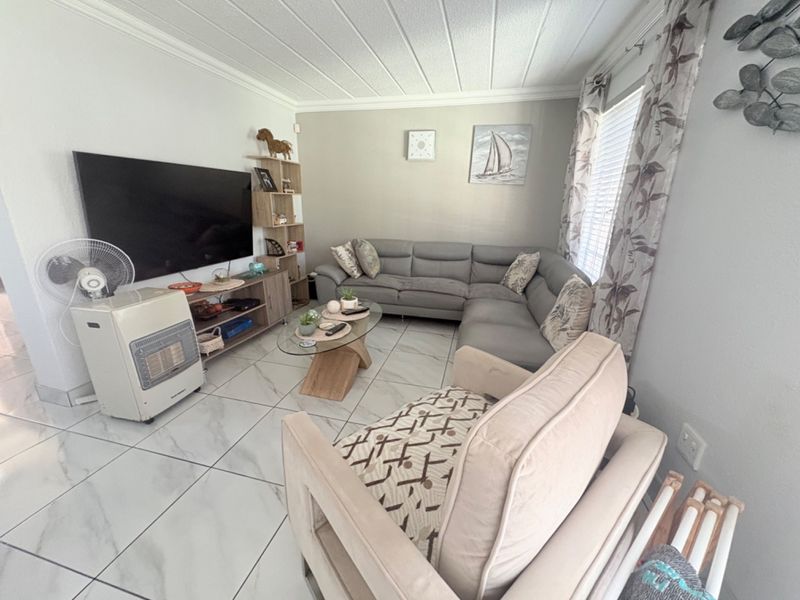 A comfortable living room featuring light-colored marble-look floor tiles, coved ceilings, and neutral wall tones, creating a bright and inviting space.