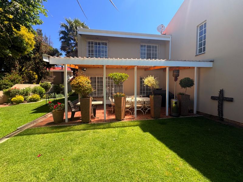 A well-maintained rear garden featuring a covered patio area with brick paving, providing a pleasant outdoor space for relaxation and entertainment.