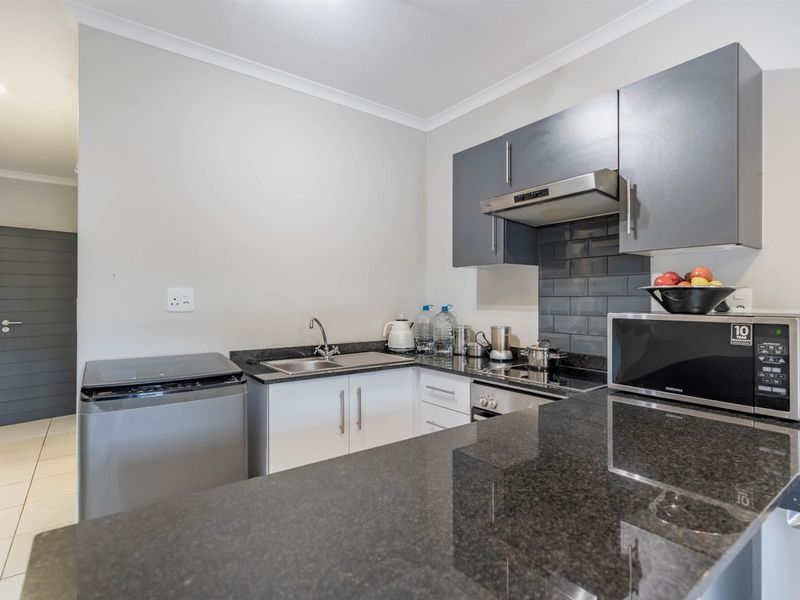 Modern kitchen featuring granite countertops, subway tile backsplash, built-in oven, extractor fan, and ample cabinetry for storage.