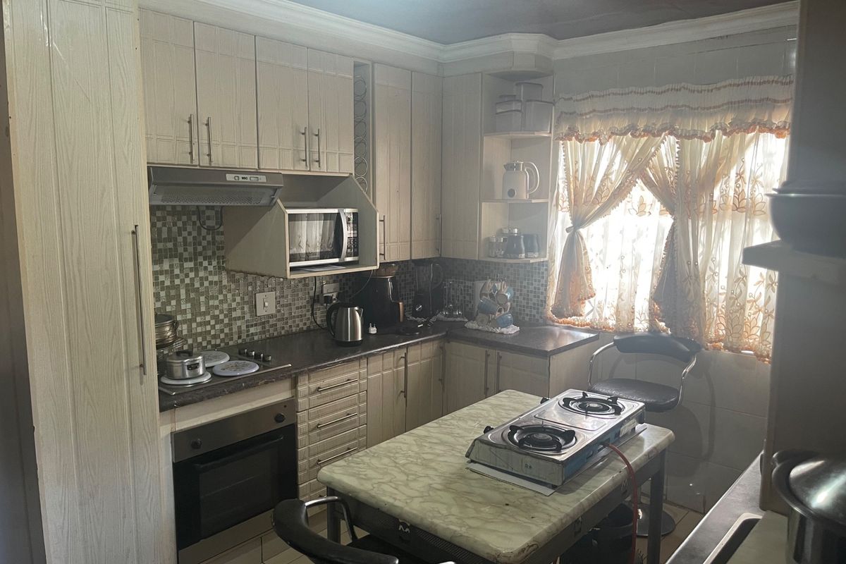 A functional kitchen featuring built-in cabinetry, mosaic tile backsplash, integrated oven, and extractor fan, offering a practical layout with ample storage space.