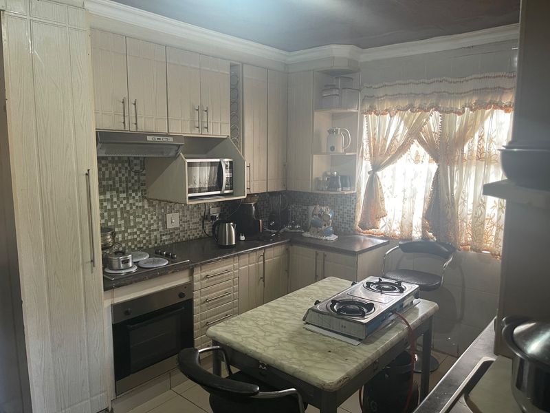 A functional kitchen featuring built-in cabinetry, mosaic tile backsplash, integrated oven, and extractor fan, offering a practical layout with ample storage space.