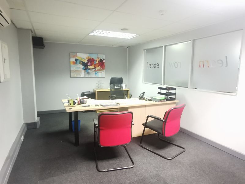 A functional office space featuring a suspended ceiling, recessed lighting, and glass partition walls, providing a professional environment for business operations.