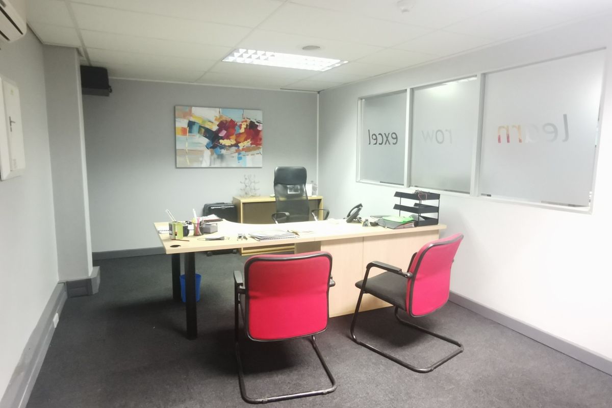 A functional office space featuring a suspended ceiling, recessed lighting, and glass partition walls, providing a professional environment for business operations.