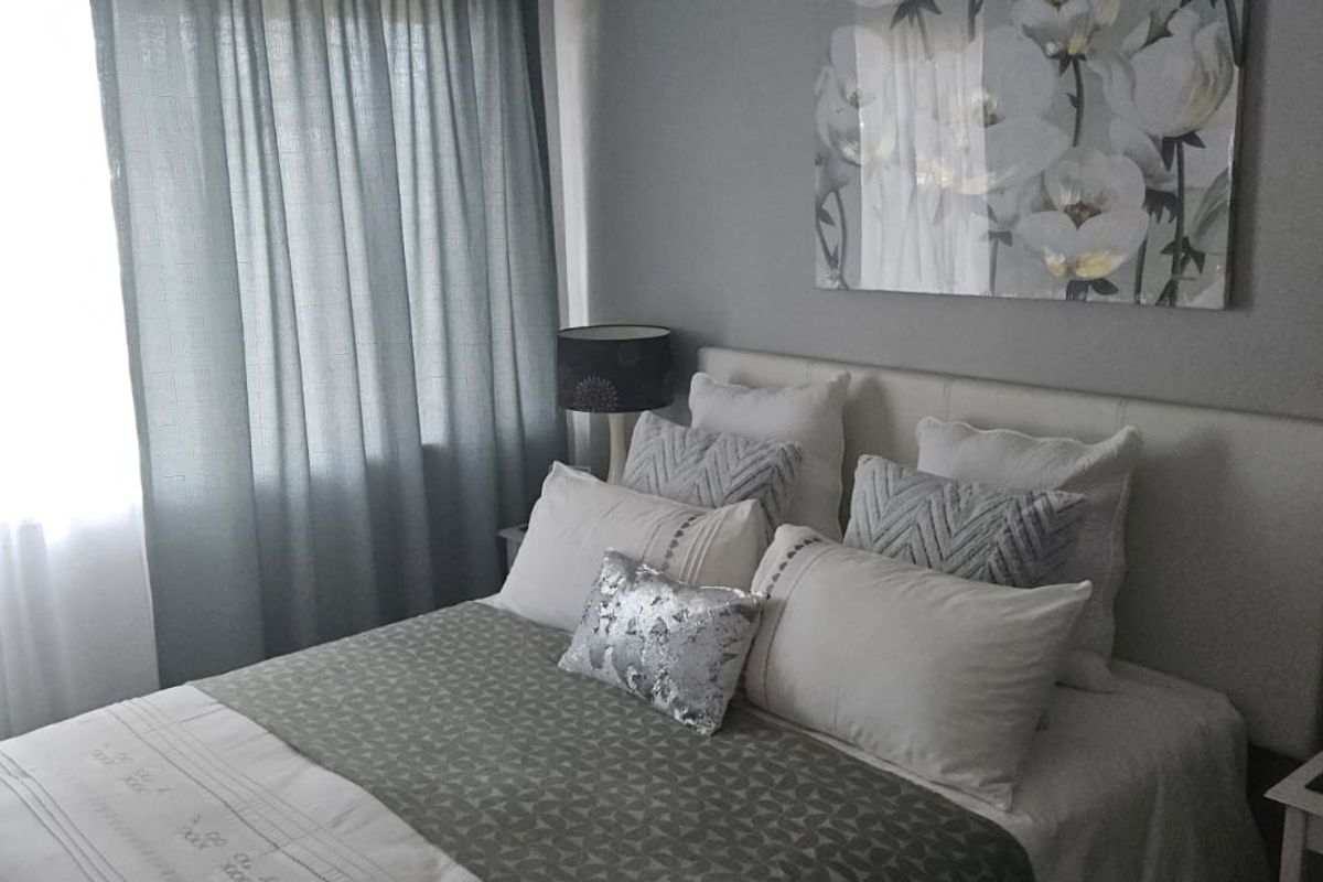 A cozy bedroom featuring a neutral color palette and a built-in headboard, creating a comfortable and inviting sleeping space.
