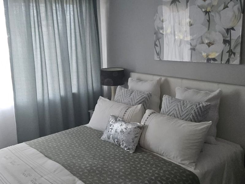 A cozy bedroom featuring a neutral color palette and a built-in headboard, creating a comfortable and inviting sleeping space.