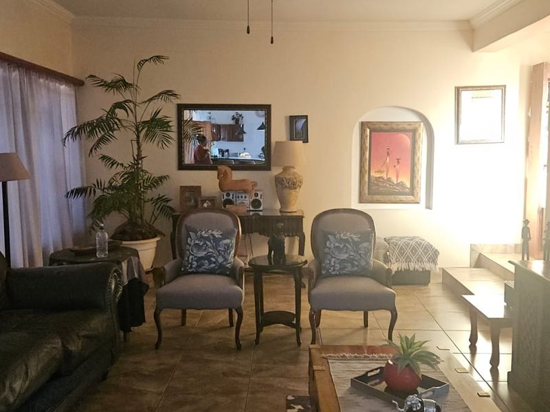 A living room featuring tiled flooring, an arched wall niche, and cove molding, providing a comfortable and traditional living space.