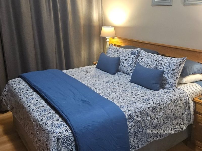 A cozy bedroom featuring laminate flooring and a built-in wooden headboard, providing a functional and comfortable sleeping space.