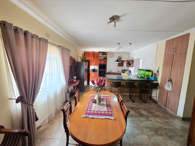 Open-plan living and dining area featuring a kitchen with built-in cabinetry, a central island, and tiled flooring throughout.