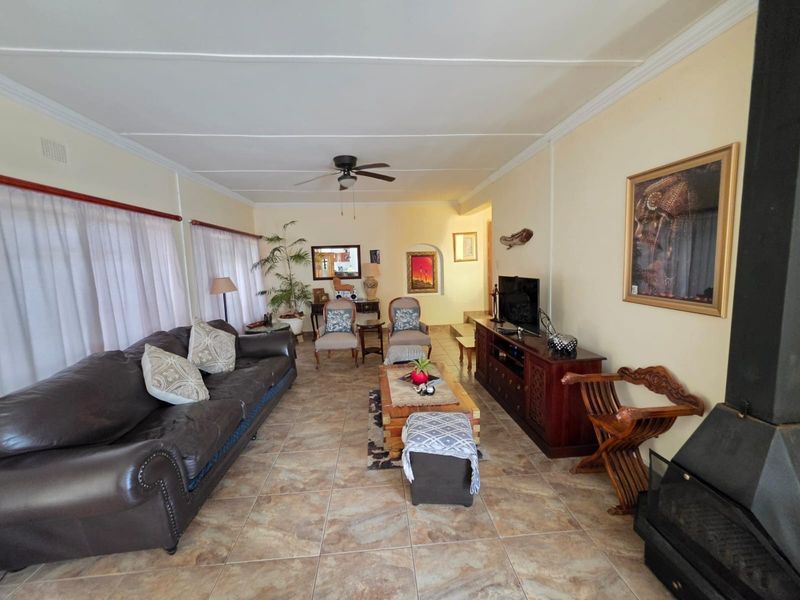Spacious living room featuring tiled flooring, a ceiling fan, and a built-in fireplace, offering a comfortable and functional layout.