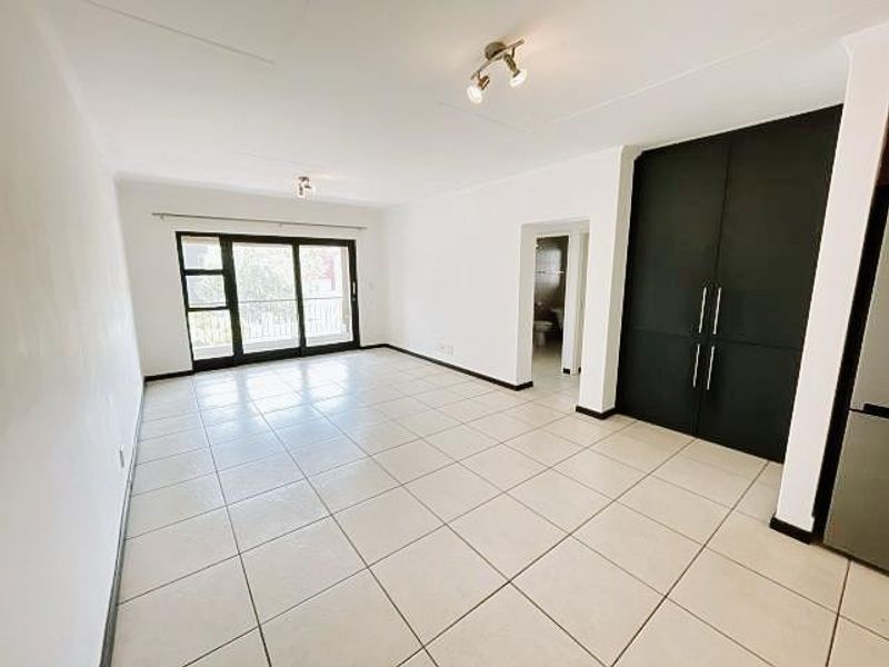 Spacious open-plan living area featuring neutral tiled flooring, modern built-in cabinetry, and large sliding glass doors leading to an outdoor space.