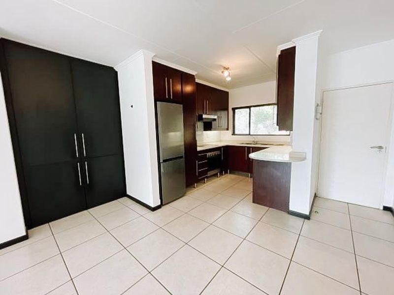 A clean, functional kitchen featuring dark wood cabinetry, a breakfast nook, tiled flooring, and integrated stainless steel appliances.