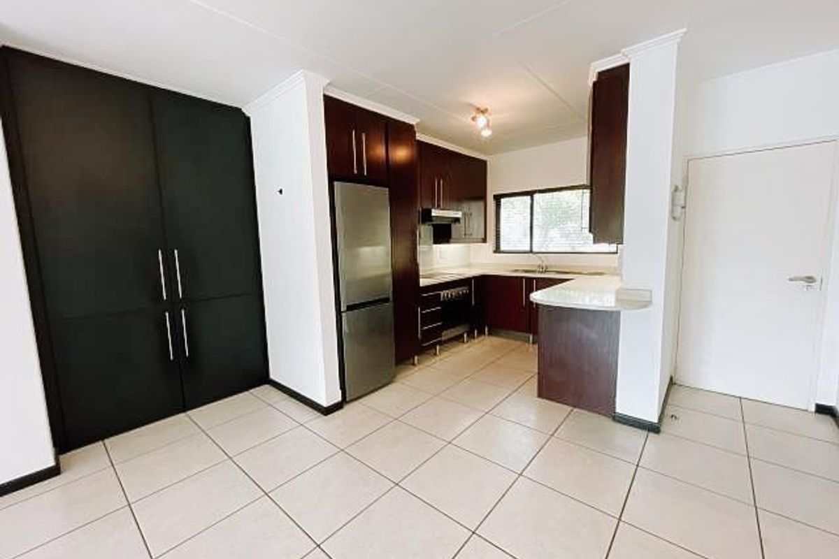 A clean, functional kitchen featuring dark wood cabinetry, a breakfast nook, tiled flooring, and integrated stainless steel appliances.