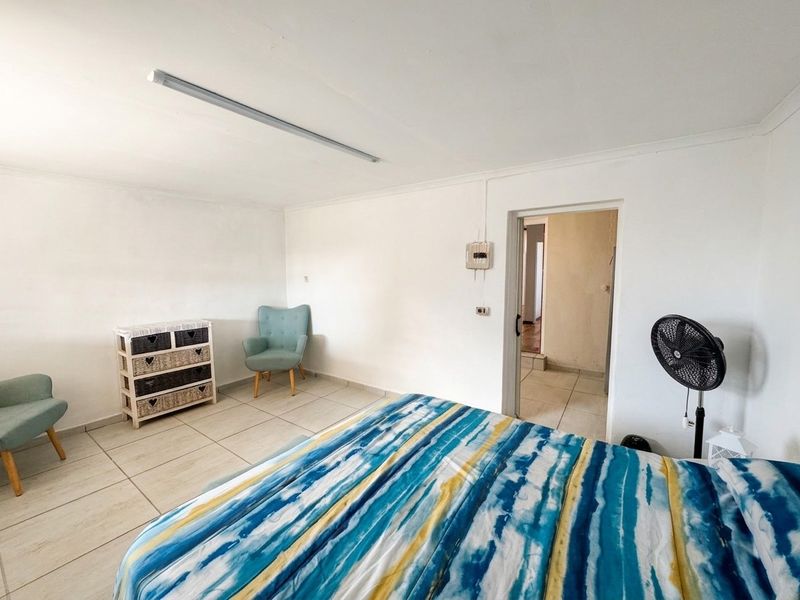 A functional bedroom featuring tiled flooring and a basic fluorescent light fixture, providing a neutral space ready for personalization.
