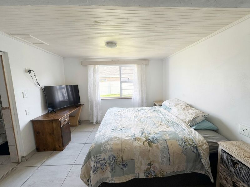 A functional bedroom featuring tiled flooring and a timber panelled ceiling, providing a neutral base for potential interior updates.