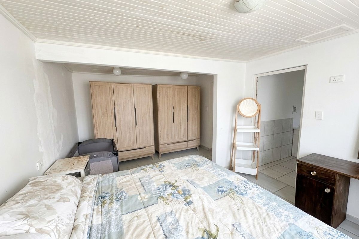 Bedroom featuring built-in wardrobes, timber ceiling, and direct access to an en-suite bathroom. The room requires cosmetic attention to wall finishes.
